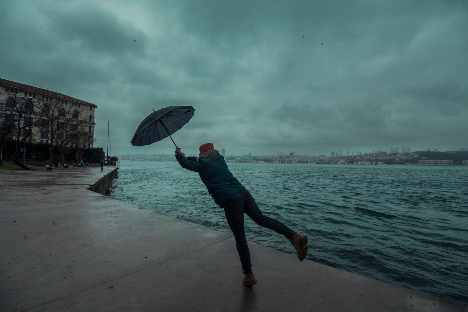 Wind Blowing Away the Umbrella Held by a Man on the Seashore