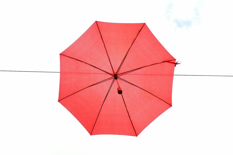 A vibrant red umbrella hanging against a clear sky, creating a striking contrast.