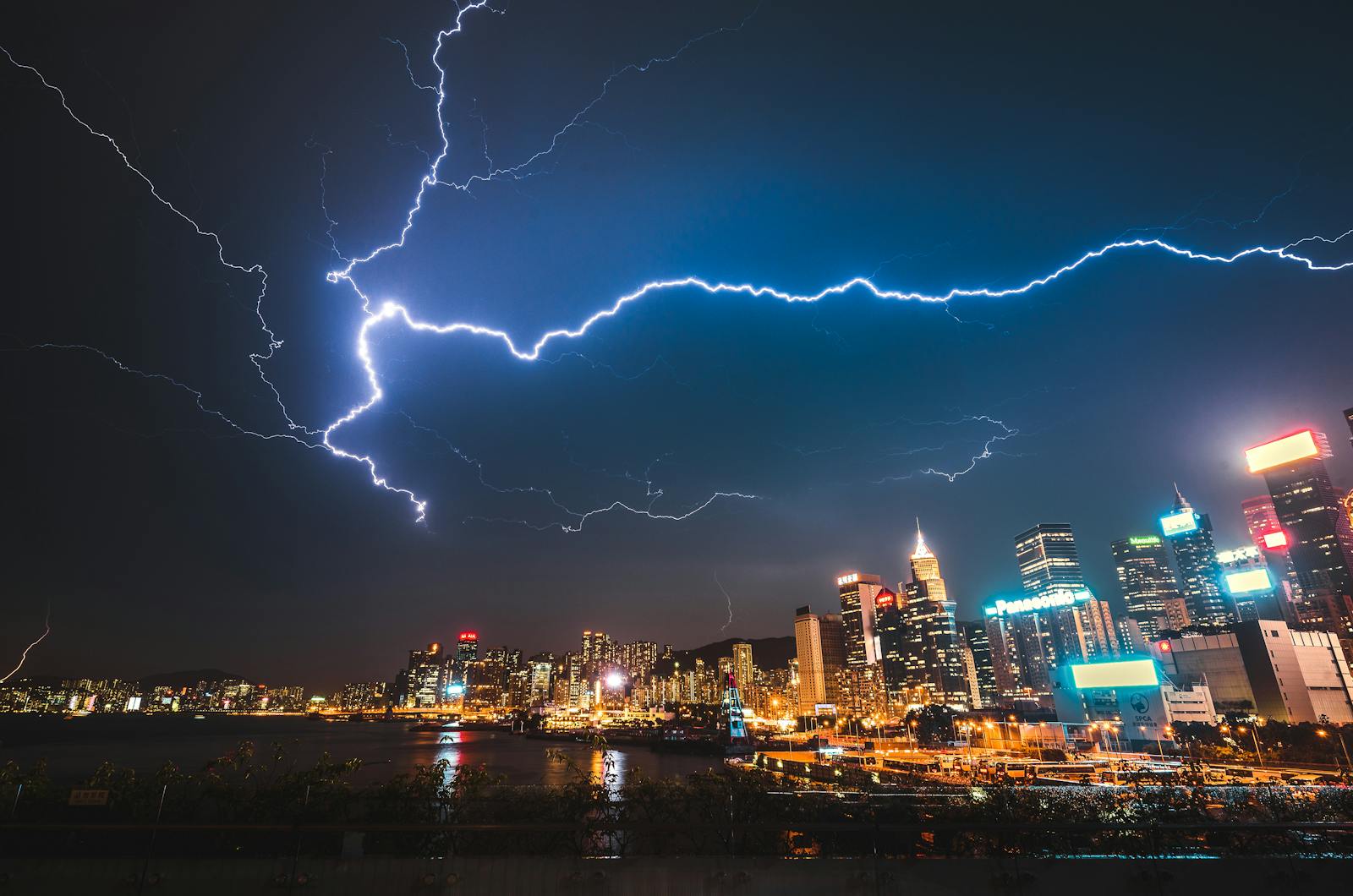 A striking image of a city skyline illuminated by a powerful lightning storm at night.