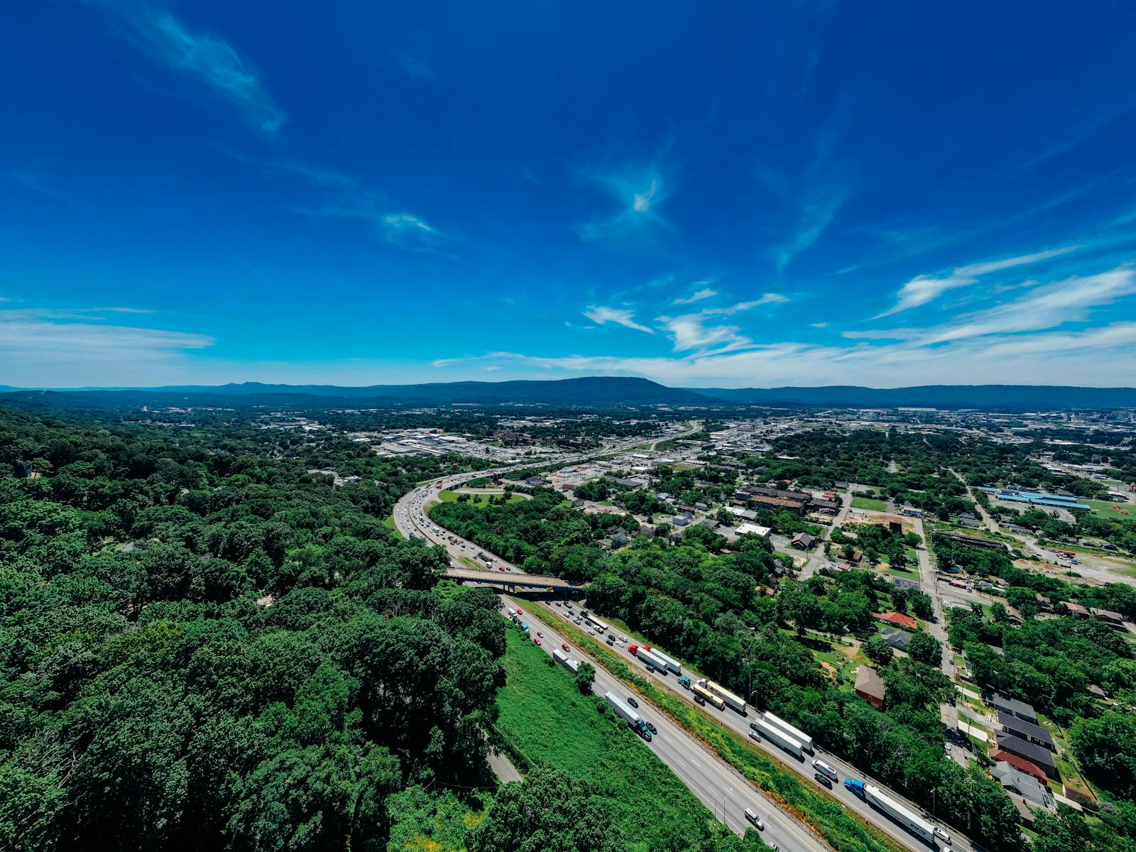 Explore the vibrant aerial view of Chattanooga with lush greenery and bustling highways on a sunny day.