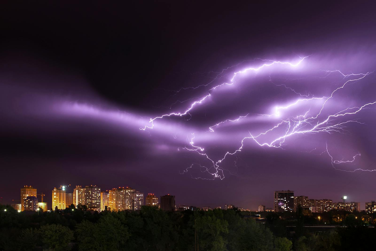 An electrifying lightning storm illuminates a modern city skyline at night, showcasing nature's power.