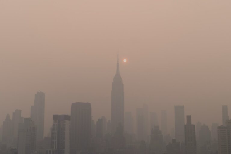 a foggy city skyline with the sun in the distance
