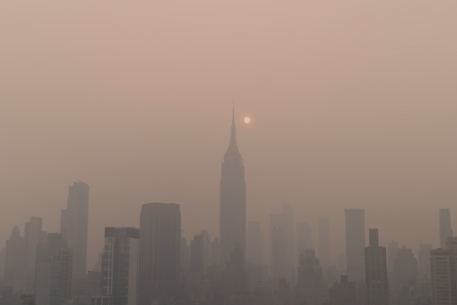 a foggy city skyline with the sun in the distance