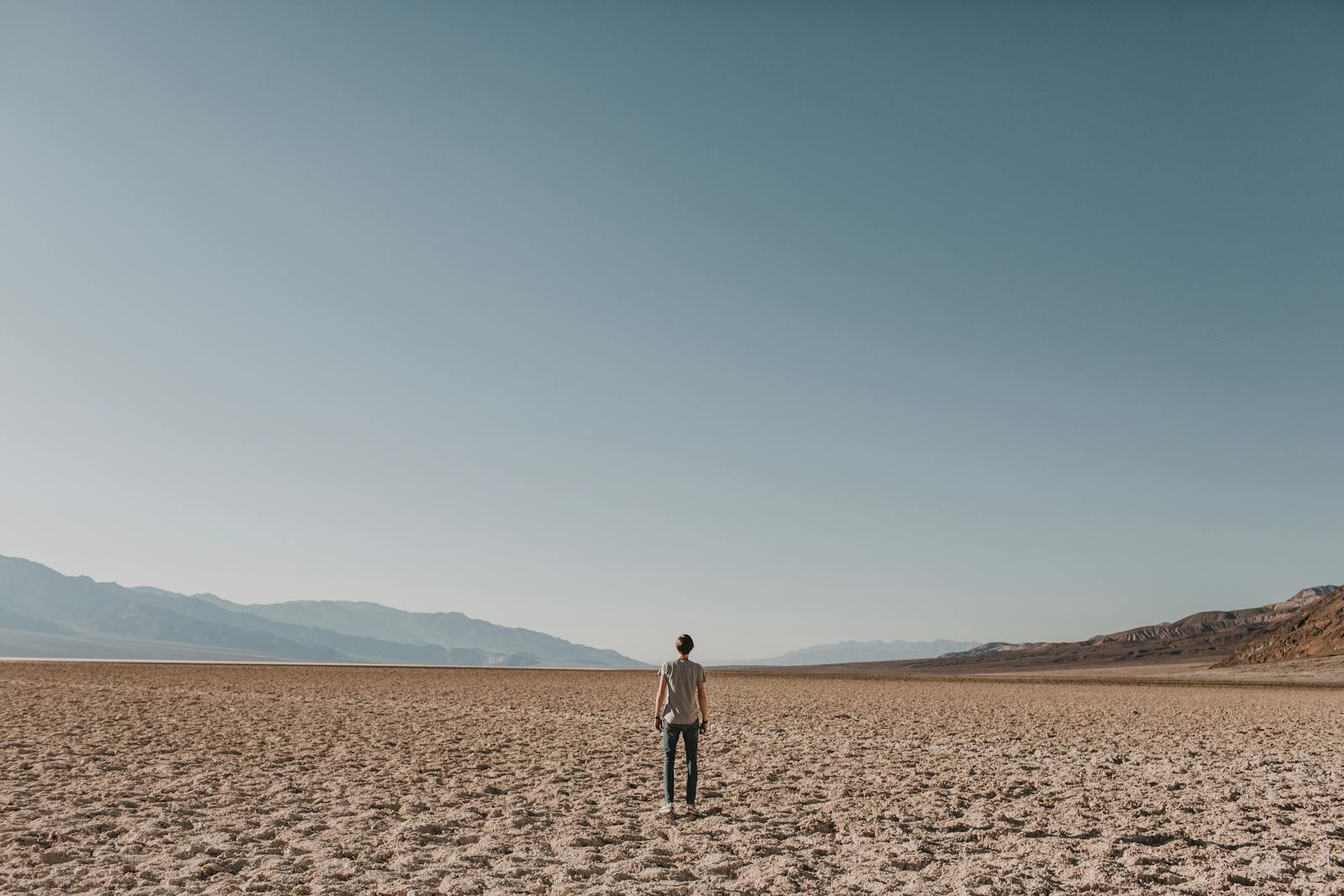 A solitary person stands in a vast desert, symbolizing isolation and exploration.