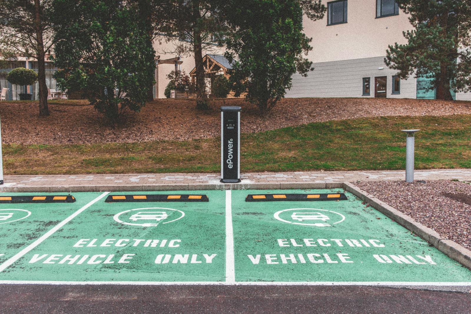 Green electric vehicle parking with charging station in urban environment.