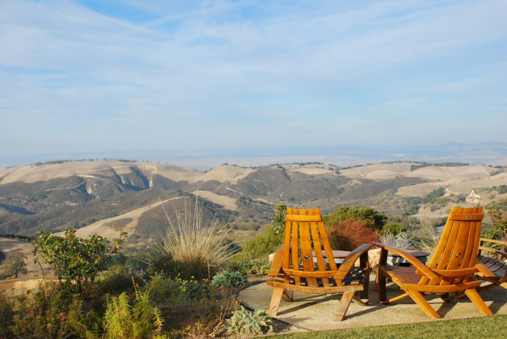 two brown wooden armchairs on cliff