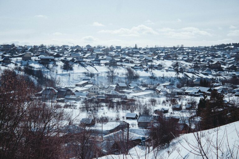 A serene snowy village landscape under a clear blue sky, showcasing winter beauty.