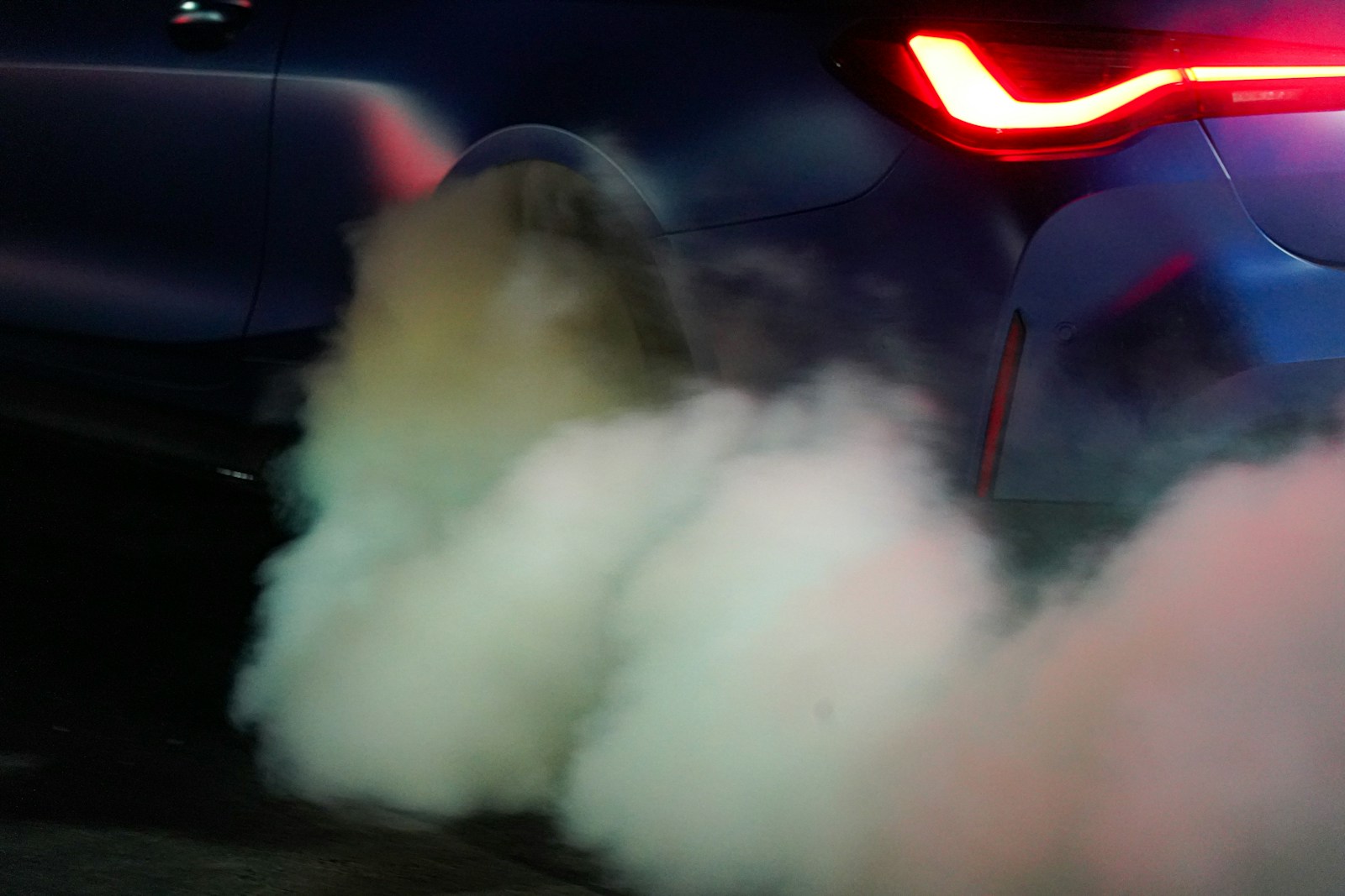 Car exhaust billows out into the night.