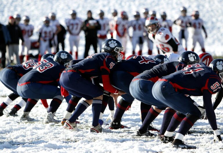 Dynamic image of athletes playing American football on a snowy field, showcasing teamwork.
