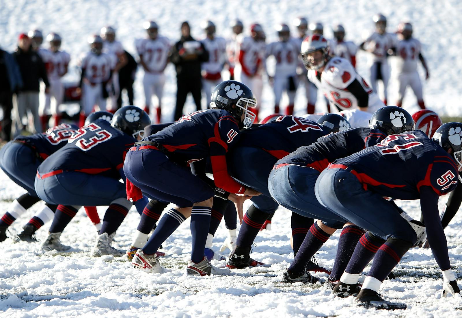 Dynamic image of athletes playing American football on a snowy field, showcasing teamwork.