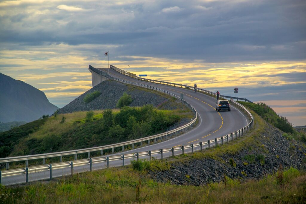 A car driving down a road next to a hill