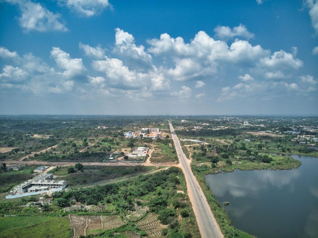 Aerial view of Yamoussoukro, Côte d'Ivoire, showcasing suburban landscapes, roads, and a lake.
