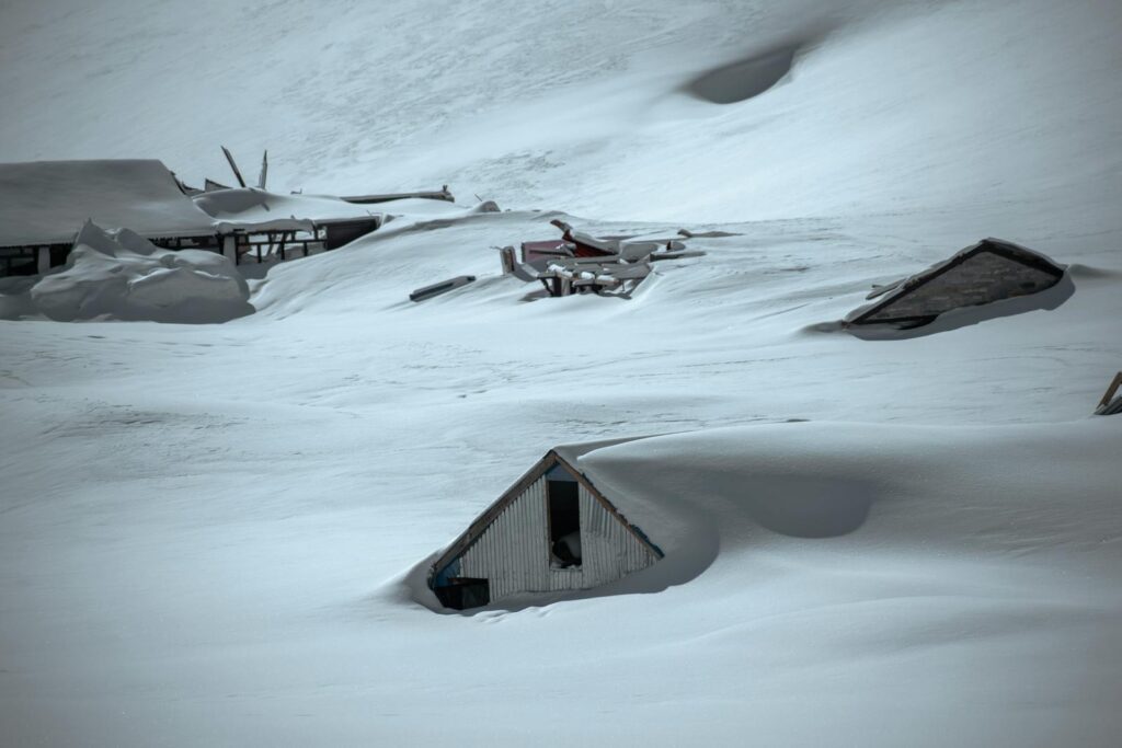 A striking image of snow-covered houses showing the aftermath of an avalanche in winter.