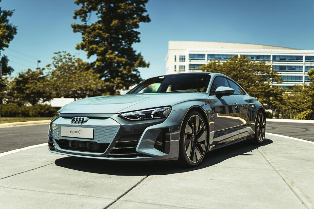 A luxurious Audi e-tron GT electric car parked in a modern urban area under clear skies.