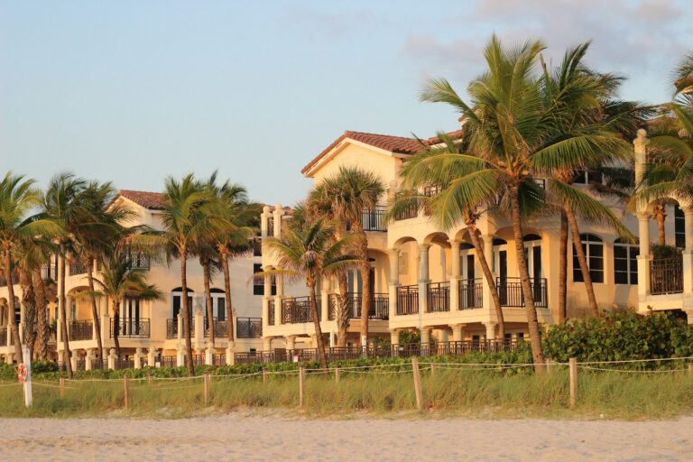 A row of houses on a beach with palm trees