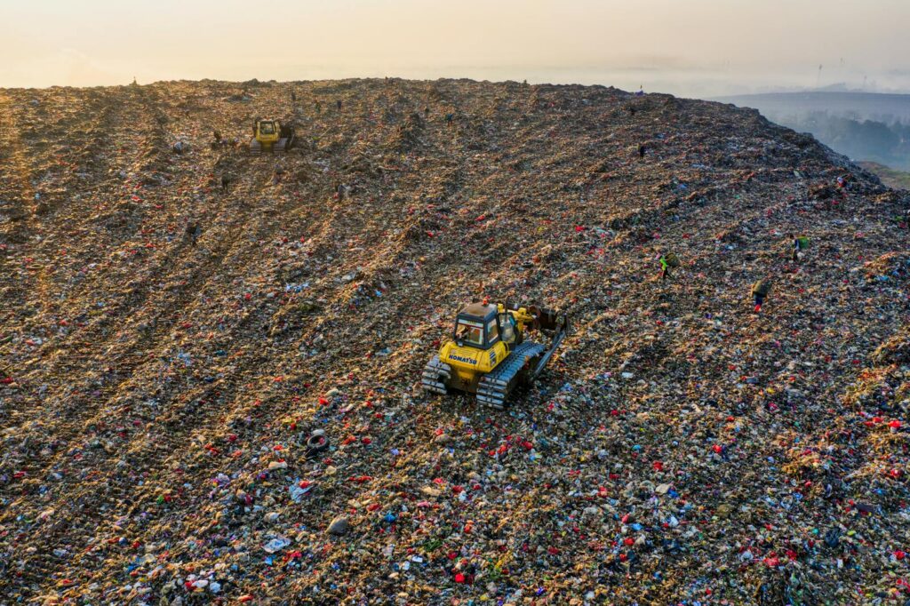 Drone shot capturing environmental impact at a landfill in West Java with visible machinery.