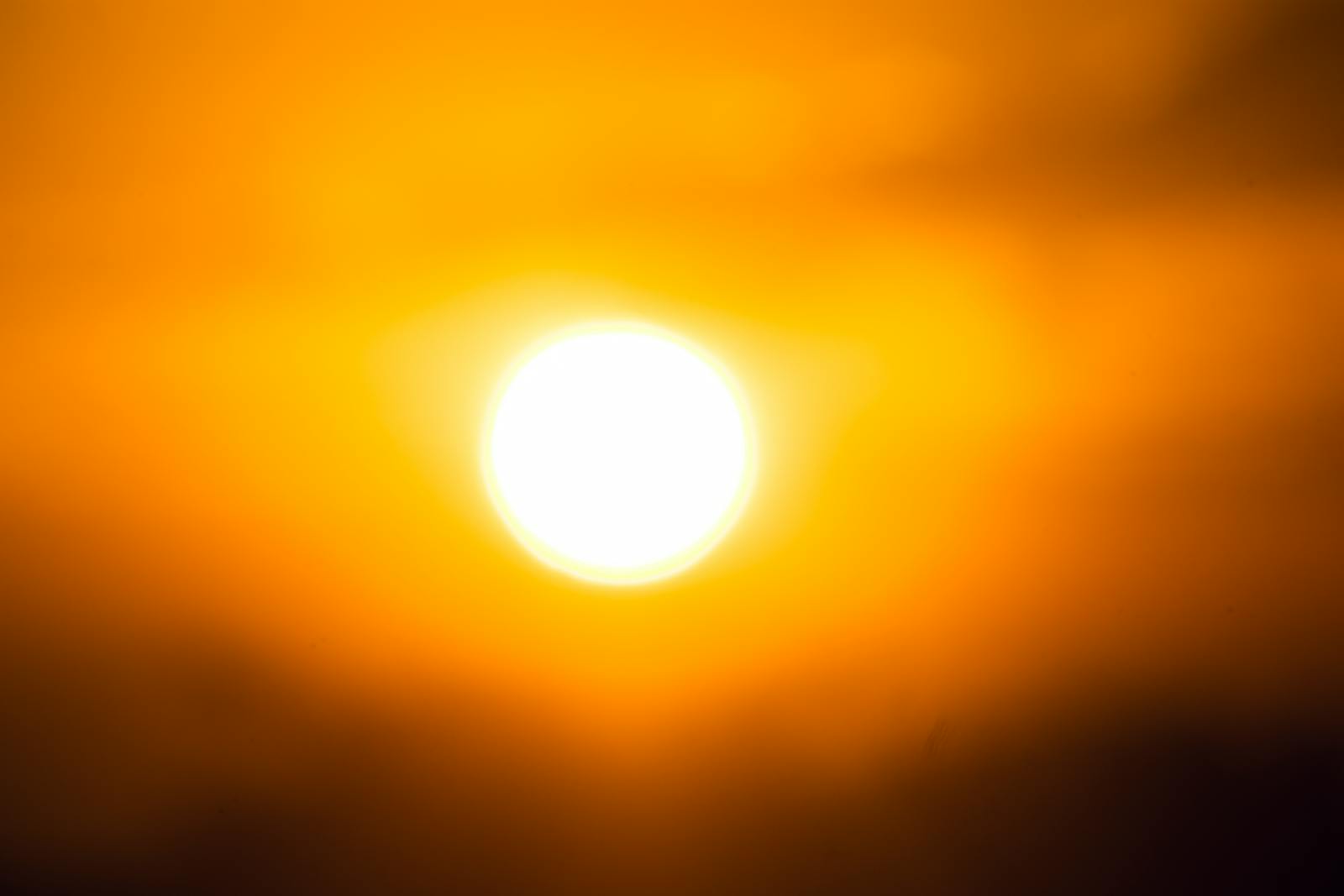 Vivid image of the sun against an orange sky, capturing twilight's essence.