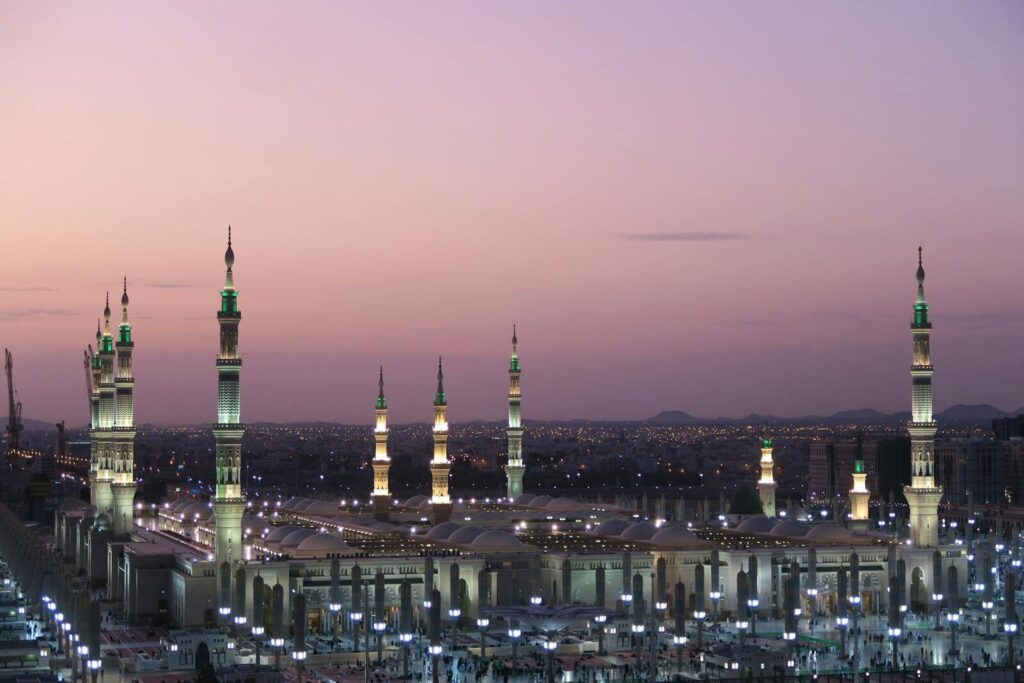 Al-Masjid an-Nabawi with its illuminated minarets at twilight in Medina, Saudi Arabia.