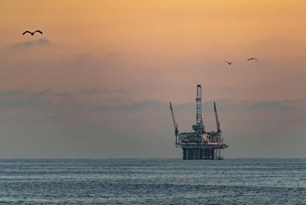 Oil platform silhouetted against a vibrant sunset in Huntington Beach, California.