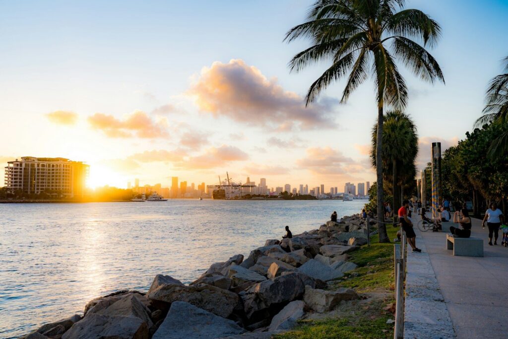people walking on a sidewalk next to a body of water