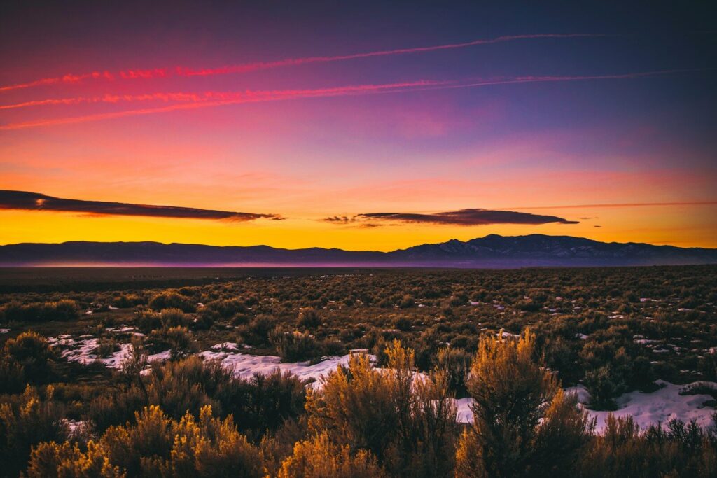 the sun is setting over the mountains in the desert