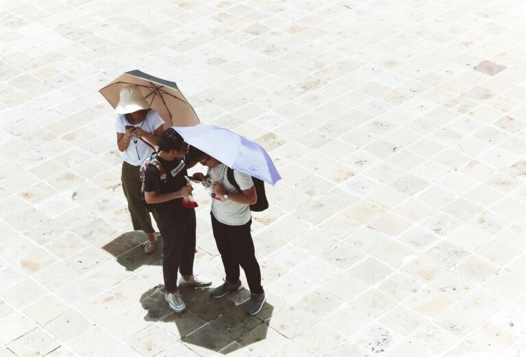 Tourists use umbrellas for shade on a sunny day in Bangkok, Thailand captured from above.