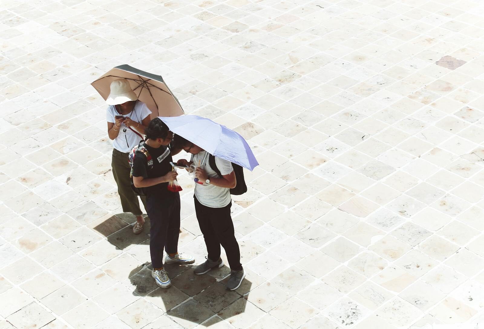 Tourists use umbrellas for shade on a sunny day in Bangkok, Thailand captured from above.
