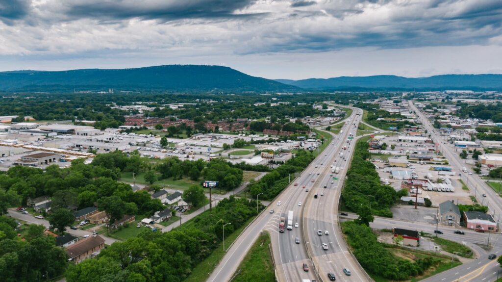 Aerial view of a busy highway in Chattanooga with lush greenery and urban landscape under cloudy skies.
