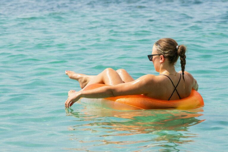 Woman relaxes on an orange float in the ocean.
