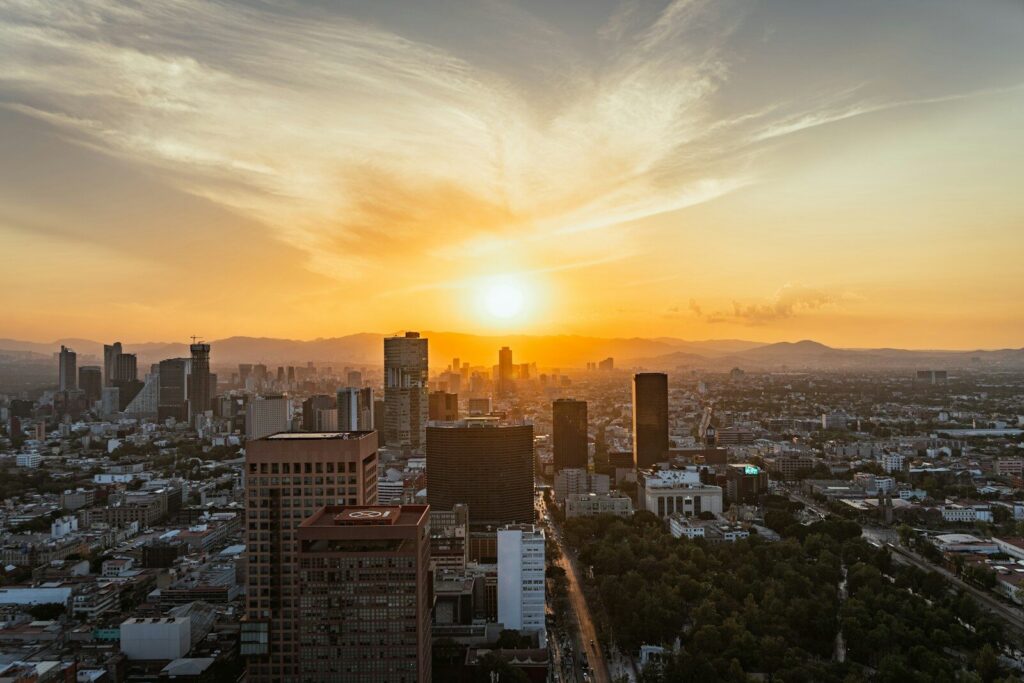 the sun is setting over a city with tall buildings