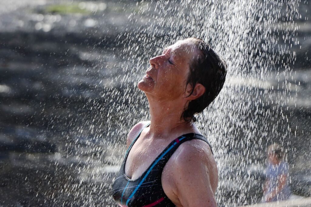 Woman enjoying a refreshing outdoor shower under a sunny sky, embracing nature.