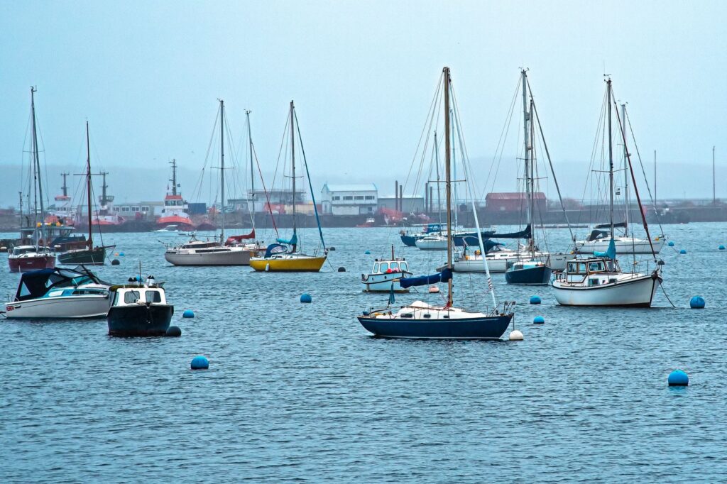 A serene view of sailboats moored in a tranquil harbor, perfect for nautical themes.