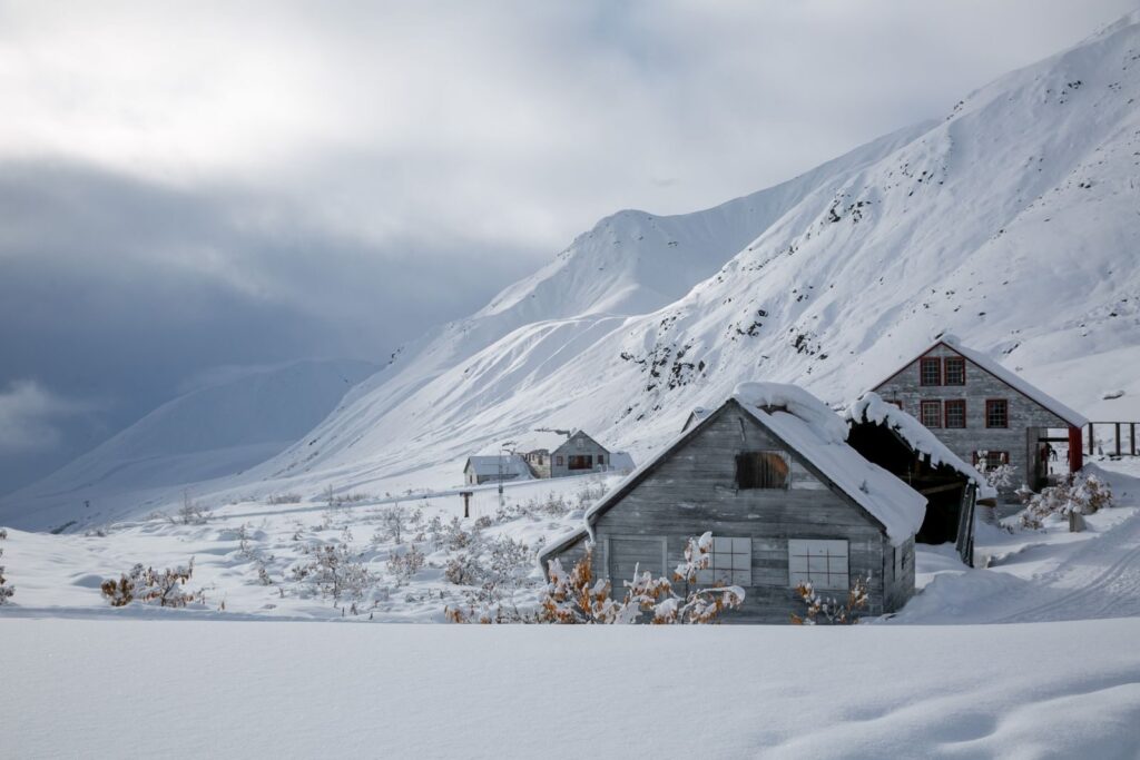 Serene winter landscape featuring snow-covered mountains and rustic houses in Palmer, Alaska.