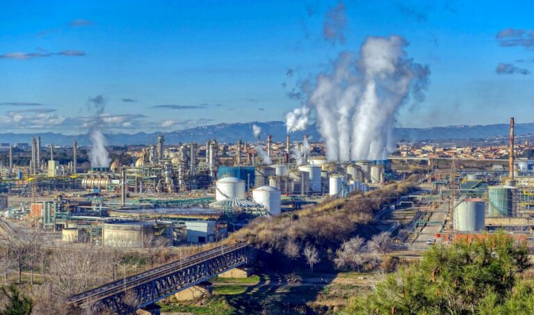 Industrial complex with steam rising from stacks.