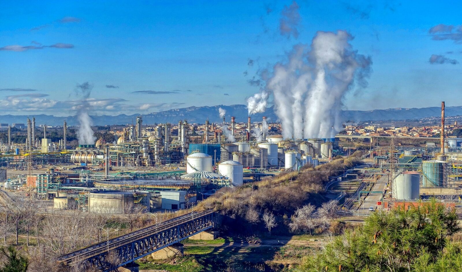Industrial complex with steam rising from stacks.