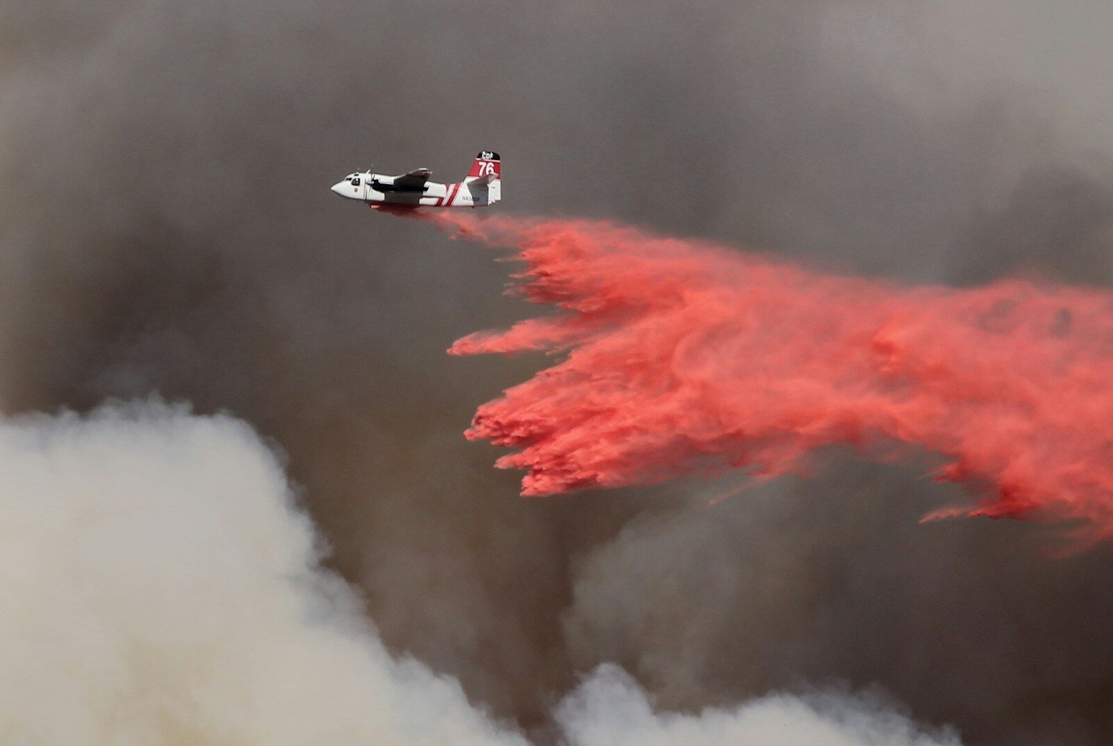 white and red airplane pouring red powder on fire