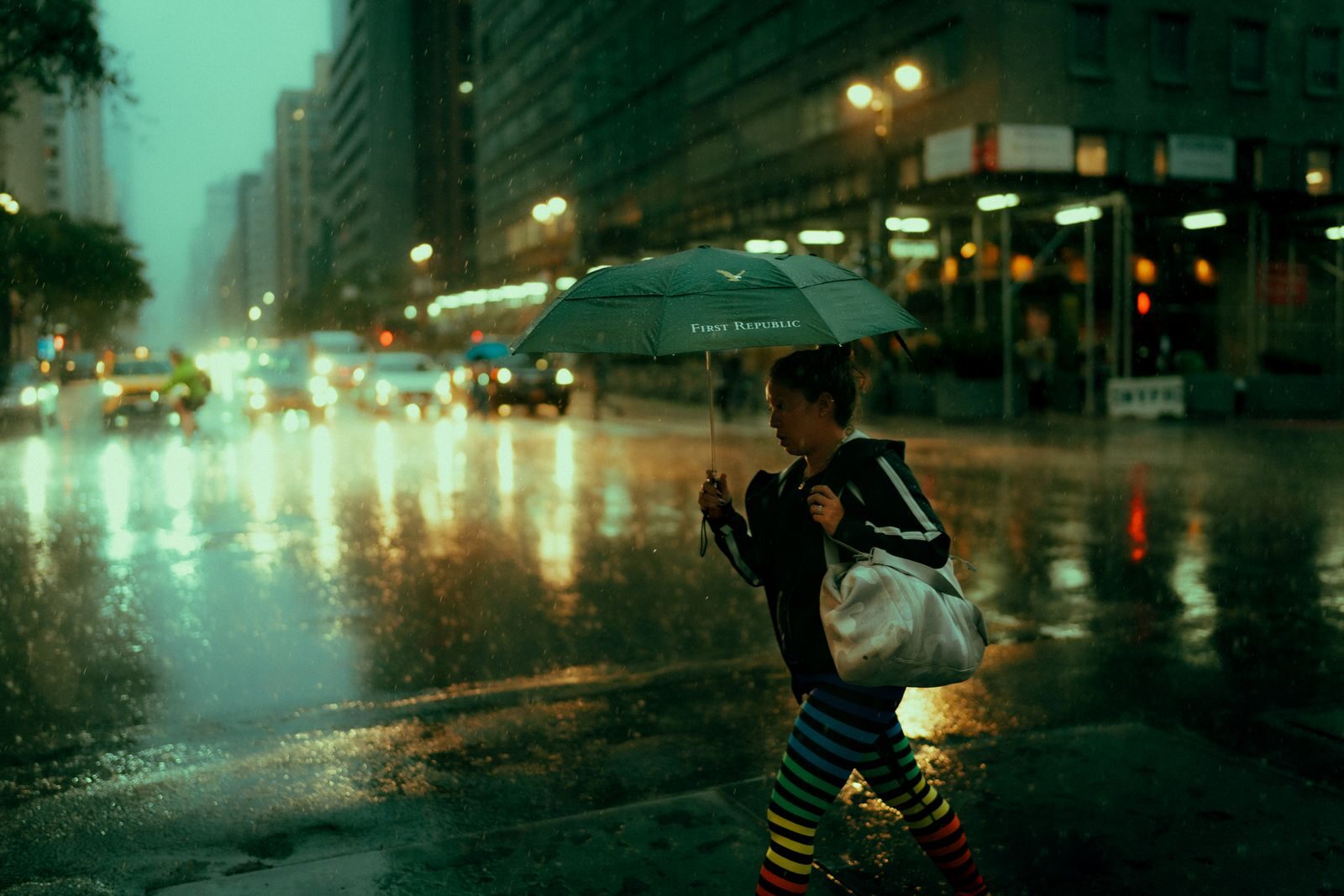 Woman walking with umbrella on a rainy New York street, reflecting urban life.