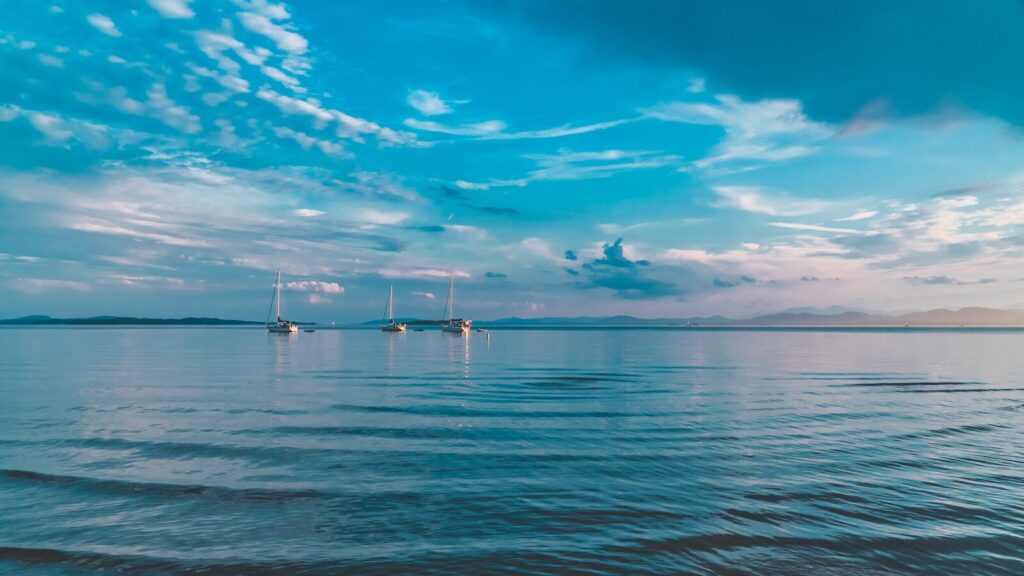 white boat on sea under blue sky and white clouds during daytime