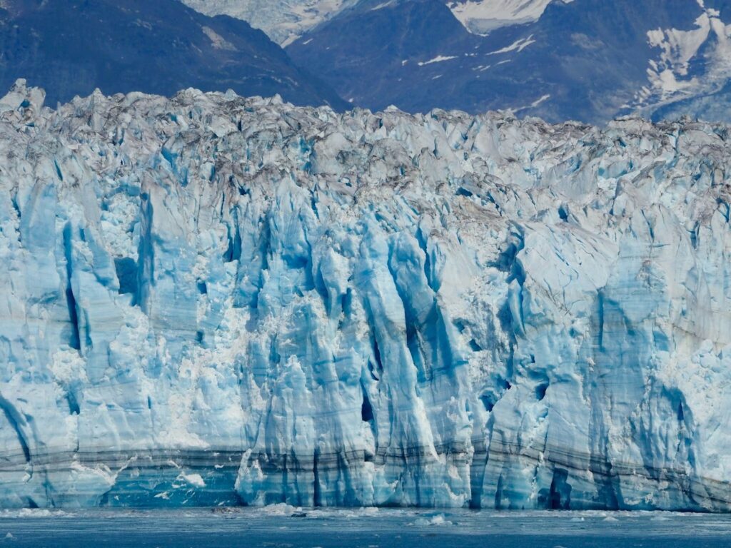 Stunning view of an Alaskan glacier with rugged mountains in the background, illustrating nature's beauty.