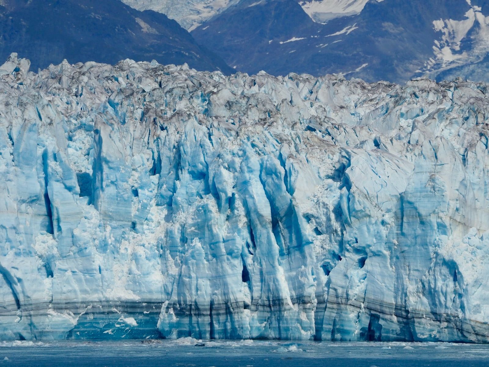 Stunning view of an Alaskan glacier with rugged mountains in the background, illustrating nature's beauty.