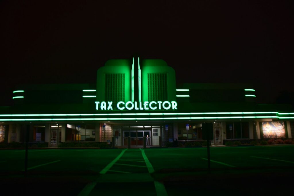 a large building with a neon sign that says tax collector