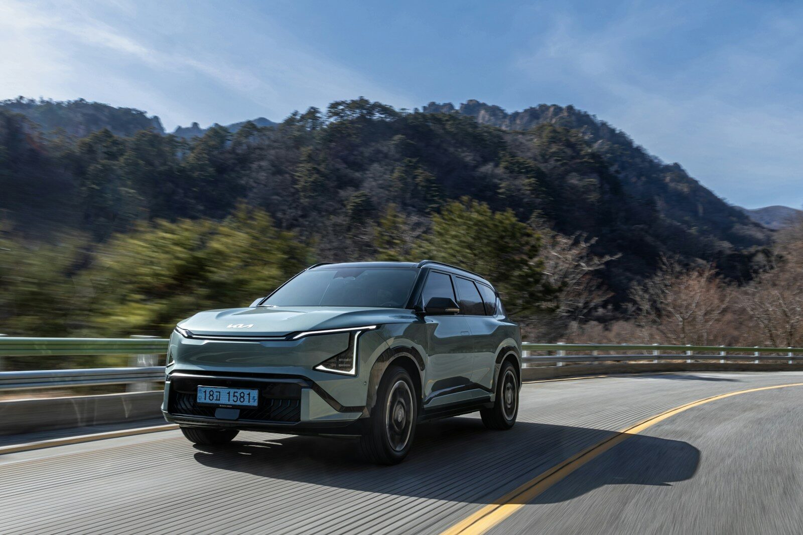 A light green suv drives on a winding road