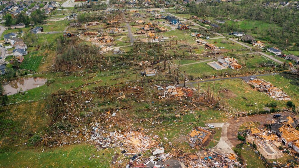 Drone dramatic view of small settlement with ruined houses and windthrown bent trees after massive thunderstorm