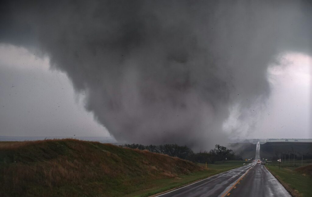 a large cloud of black smoke billows over a highway