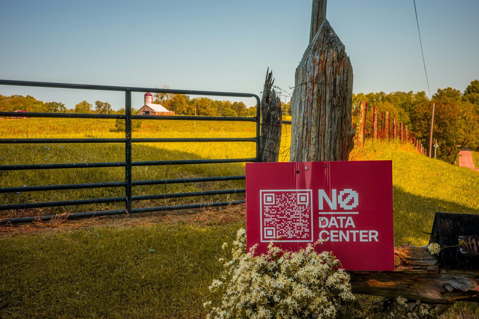 A red sign reading NO DATA CENTER with a QR code near a farm gate