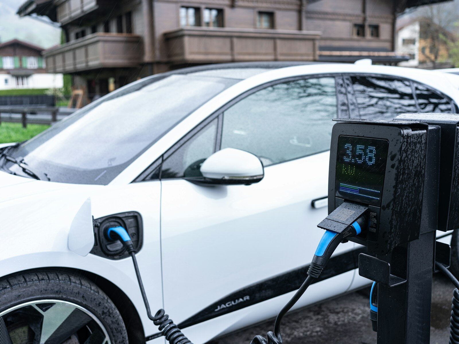 White electric car charging at a station