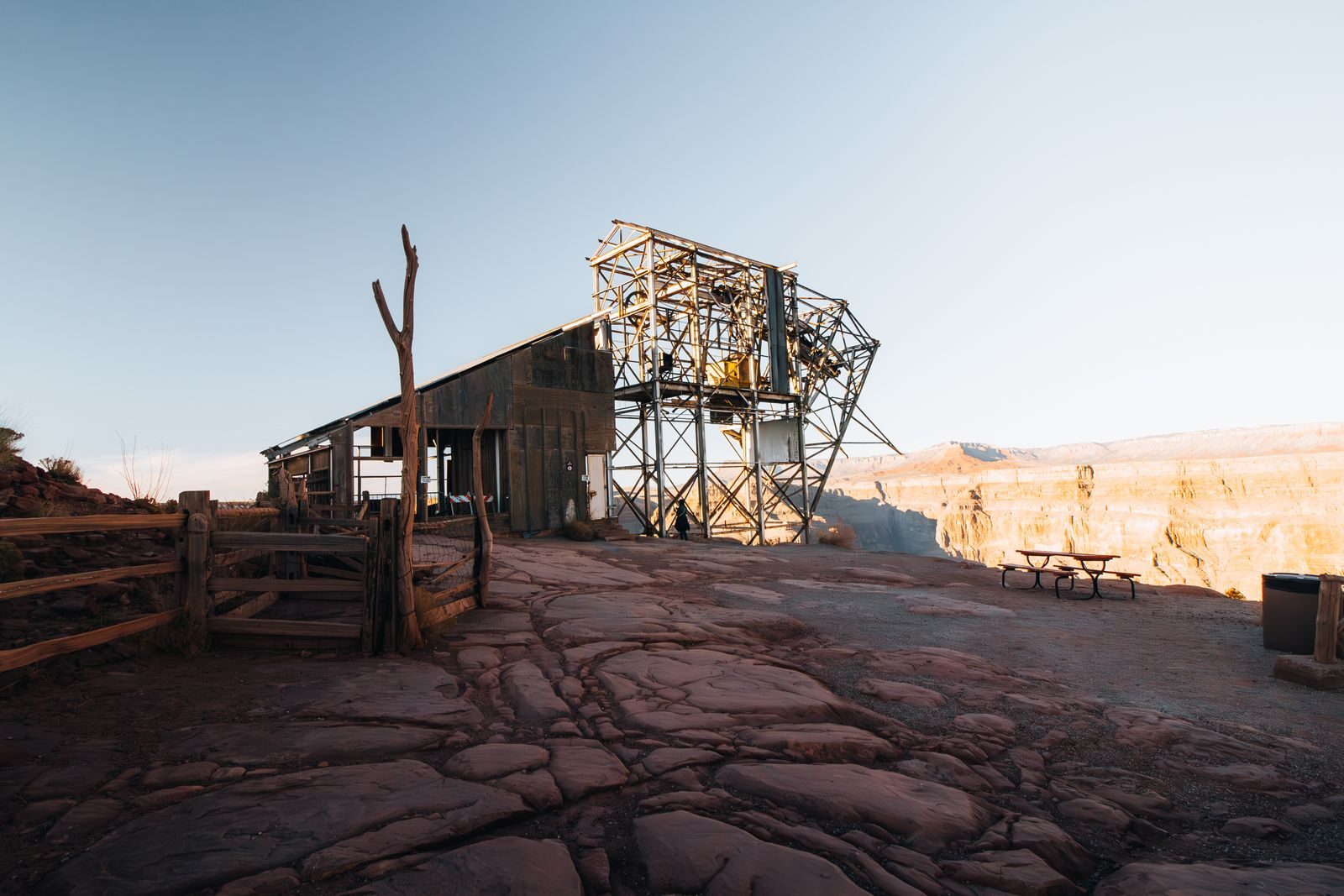 A rustic industrial structure on the rim of an Arizona canyon under a clear sky.